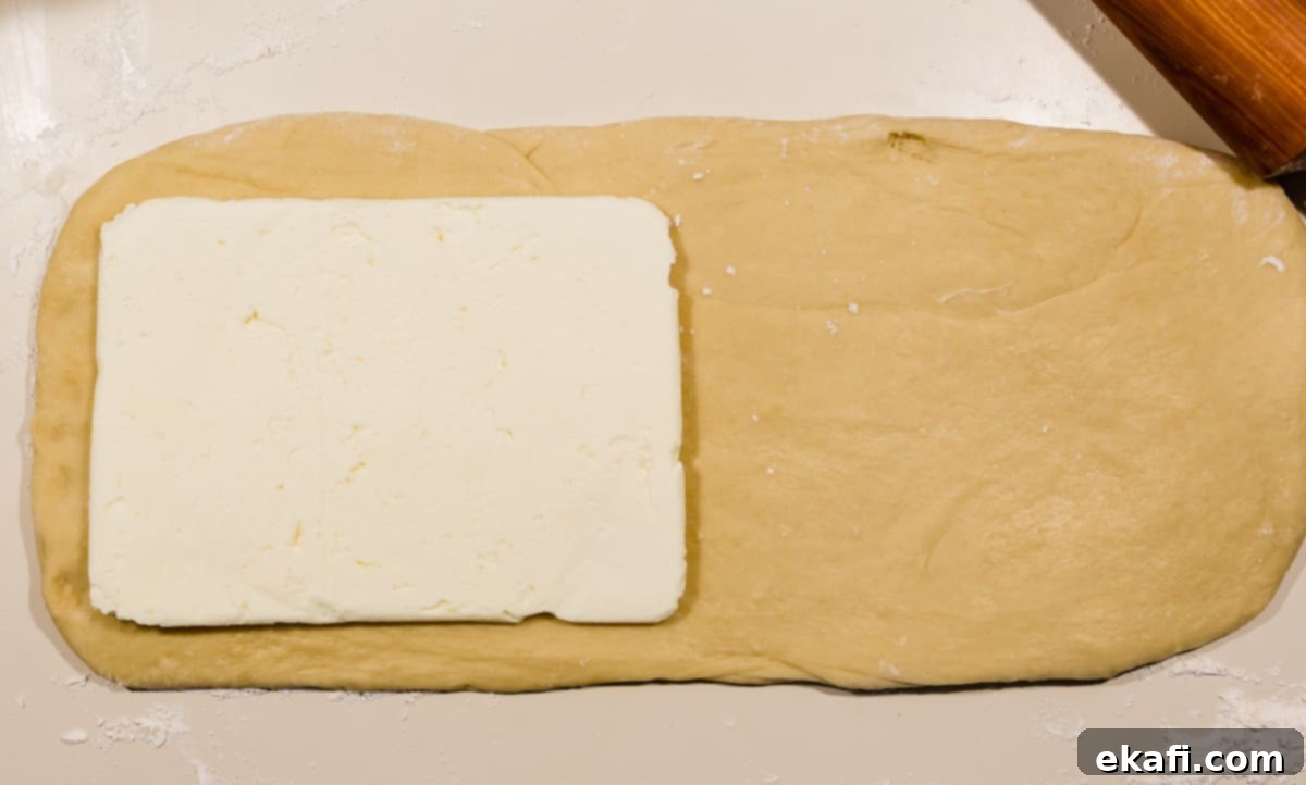 Pillowy Flaky Brioche 8 A square of flattened butter strategically placed on brioche bread dough, precisely ready to begin the lamination process.