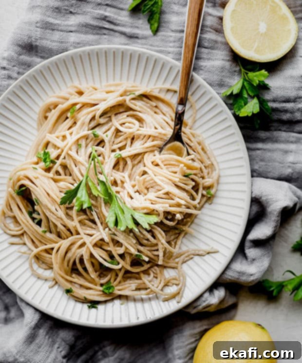 Happy Tummies Happy Kids 11 A crisp white plate showcasing a generous helping of vibrant lemon pasta, delicately garnished with fresh green parsley, ready to be savored.