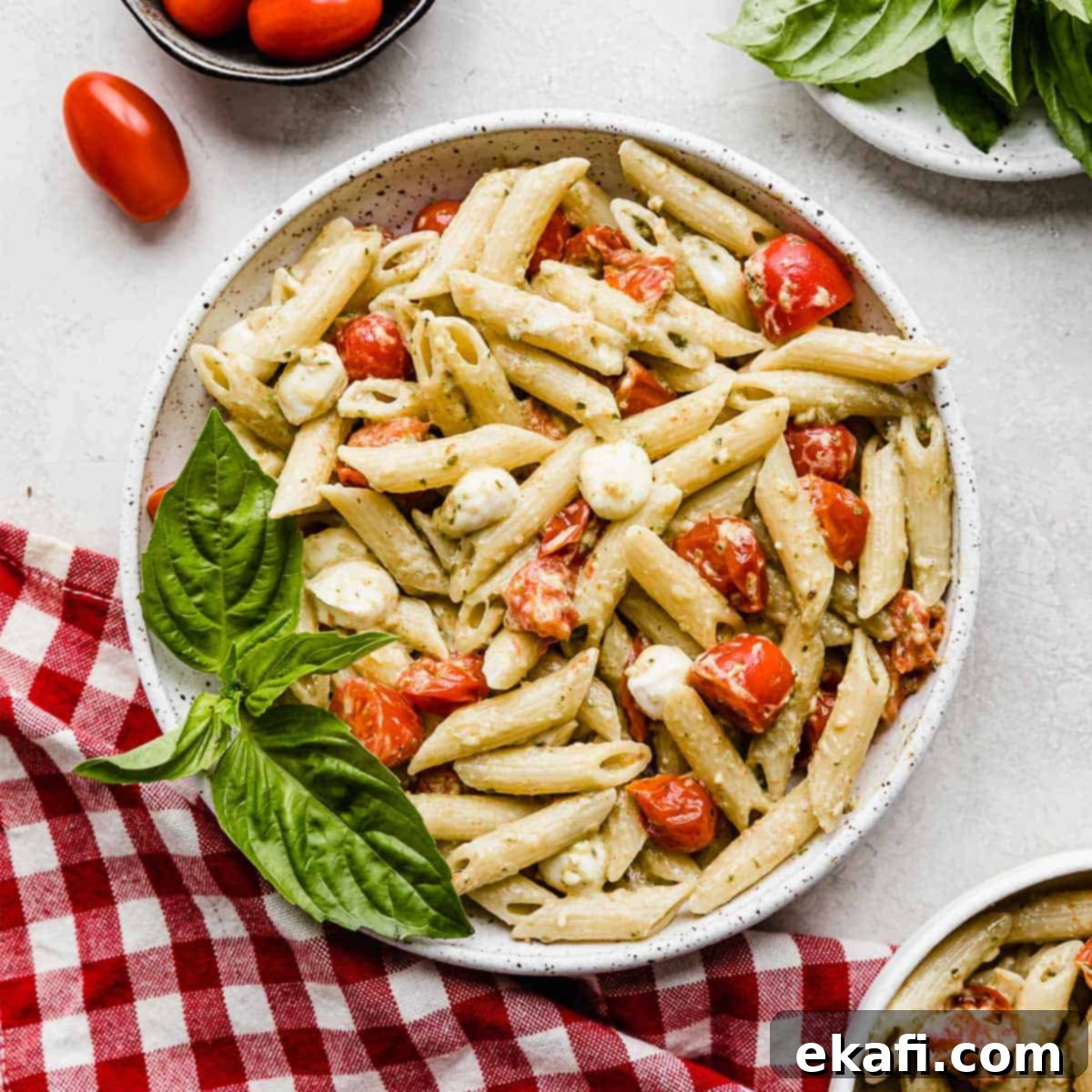 Happy Tummies Happy Kids 7 A beautifully presented bowl of creamy pesto pasta, adorned with vibrant red tomatoes and soft mozzarella balls, promising a delightful culinary experience.