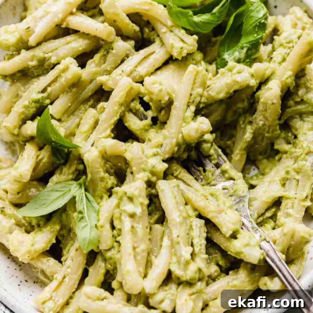 Happy Tummies Happy Kids 10 A close-up image of pasta perfectly tossed in a light green basil pesto, enhanced with creamy mashed avocado, and garnished with fresh basil leaves for a vibrant and healthy meal.