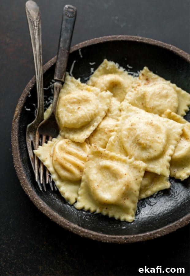 Mastering Homemade Ravioli 11 A bowl full of butternut squash filled ravioli, garnished with fresh herbs.