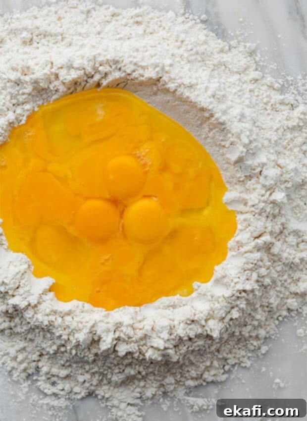 Mastering Homemade Ravioli 4 Eggs and egg yolks filling a flour mound.