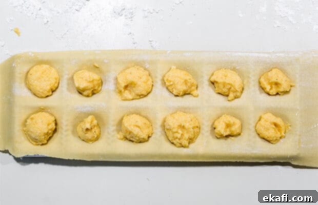 Mastering Homemade Ravioli 7 A sheet of Ravioli dough over a ravioli mold with a butternut squash filling in each mold.