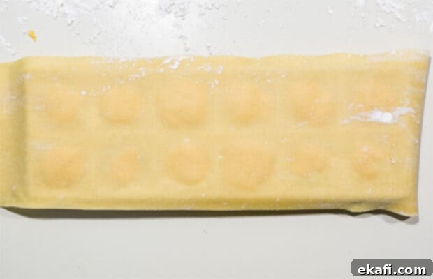 Mastering Homemade Ravioli 8 A sheet of ravioli dough covering the filled ravioli mold, ready for sealing.