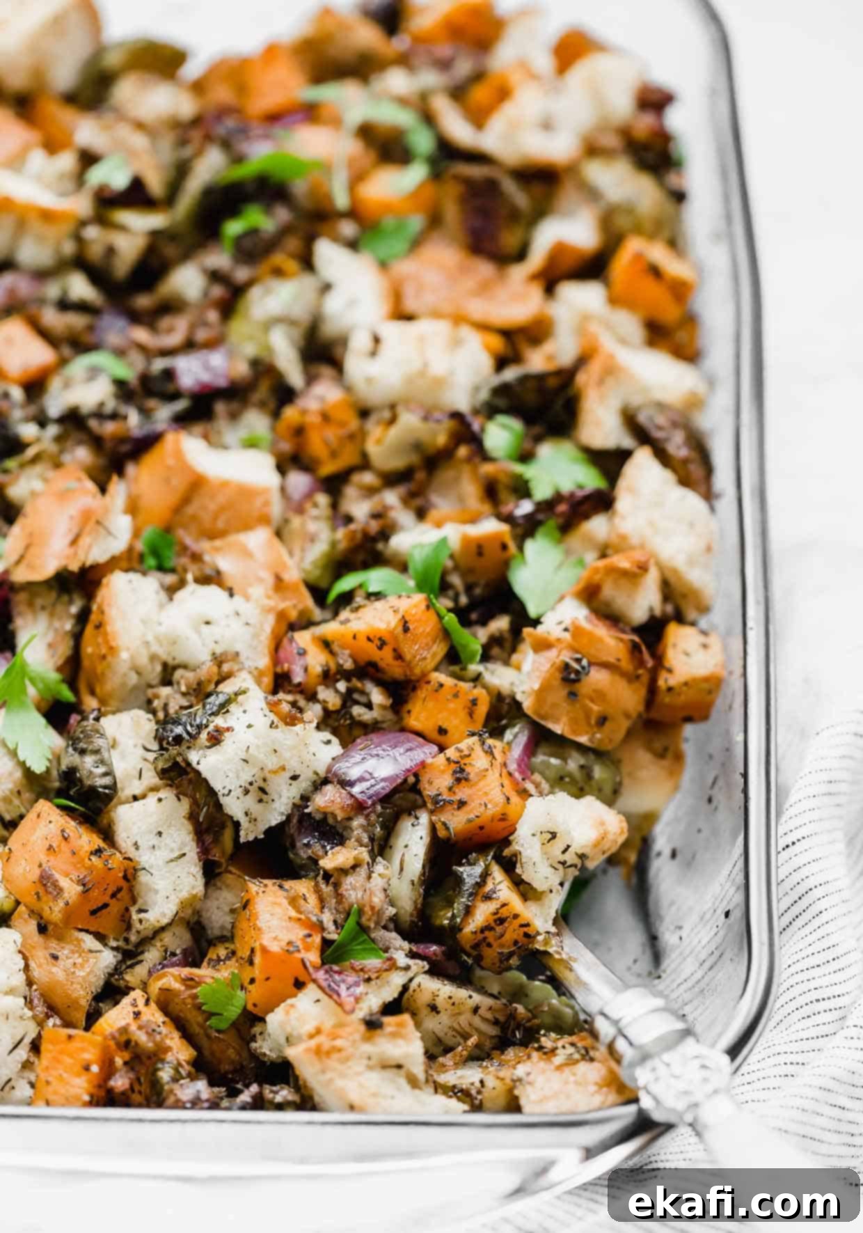 Savory Italian Sausage Dressing 2 Vegetable Stuffing in a casserole dish with a large serving spoon scooping out a portion.