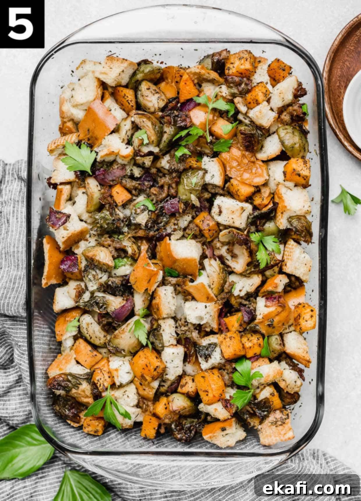 Savory Italian Sausage Dressing 5 Overhead photo of Autumn Roasted Vegetable Stuffing recipe in a glass casserole dish on a white background.