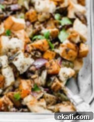 Savory Italian Sausage Dressing 8 Vegetable Stuffing in a glass baking dish, featuring purple onion, sweet potato, and Brussels sprouts.
