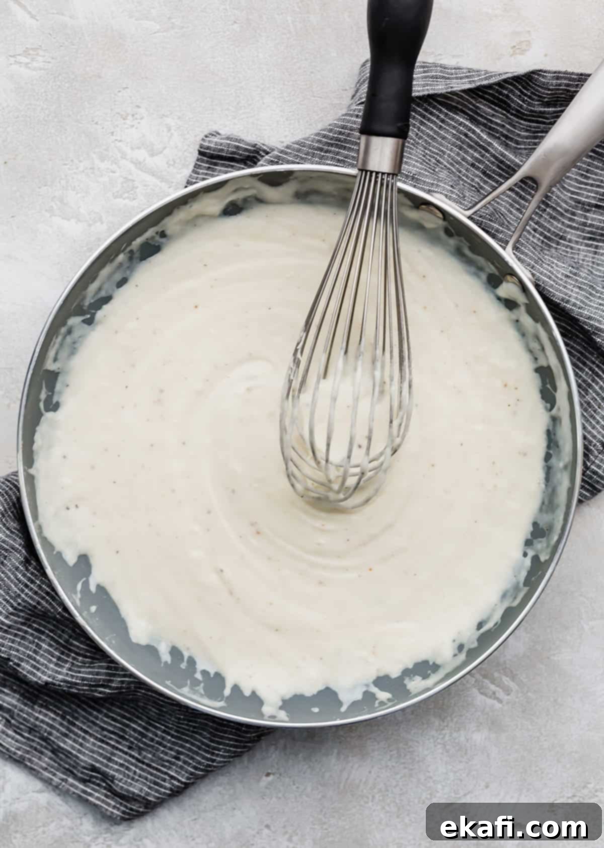 Creamy Baked Cauliflower 4 Cauliflower Gratin white sauce made with gruyere cheese in a gray skillet.