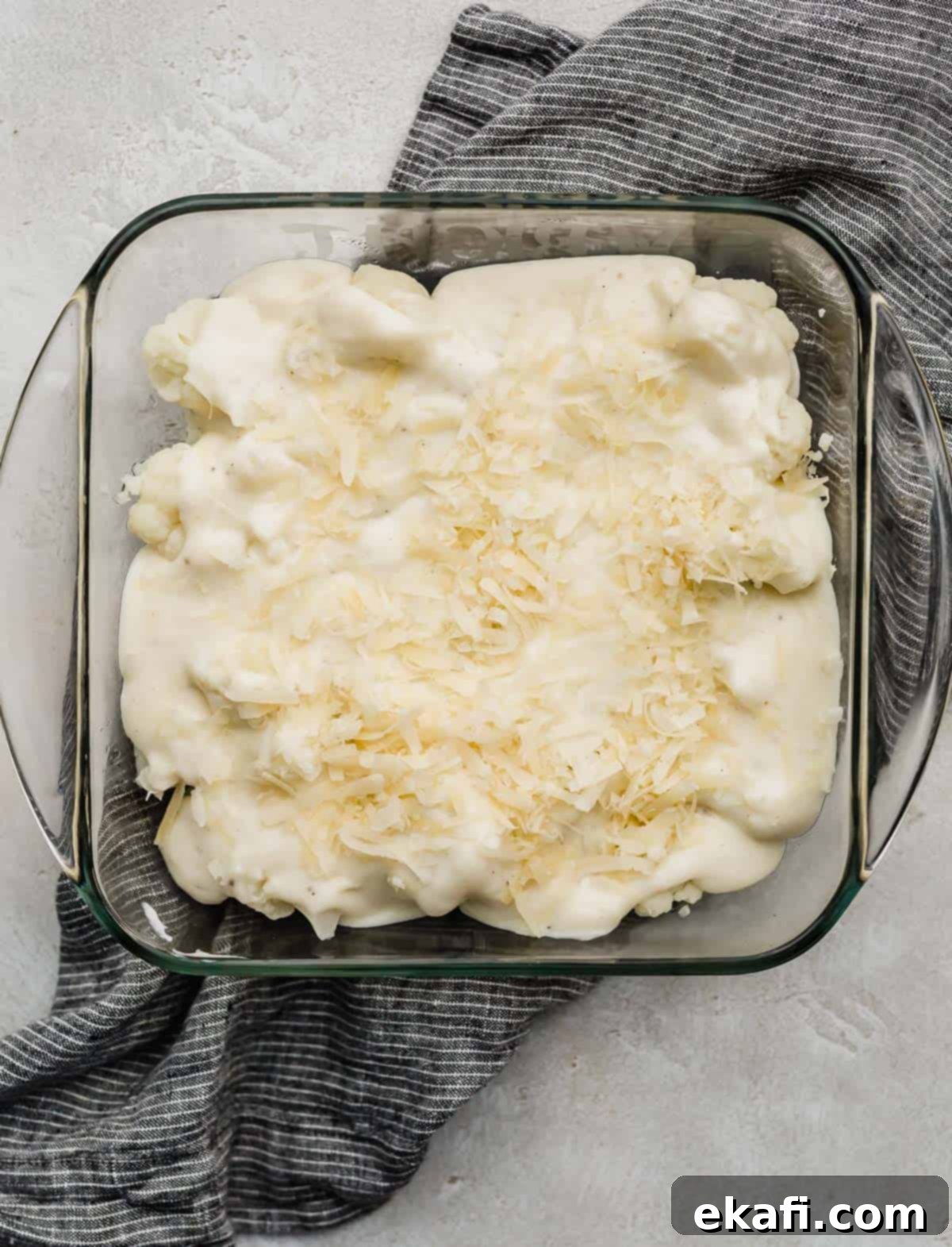 Creamy Baked Cauliflower 5 Unbaked Cauliflower Gratin topped with gruyere cheese in a square casserole dish.
