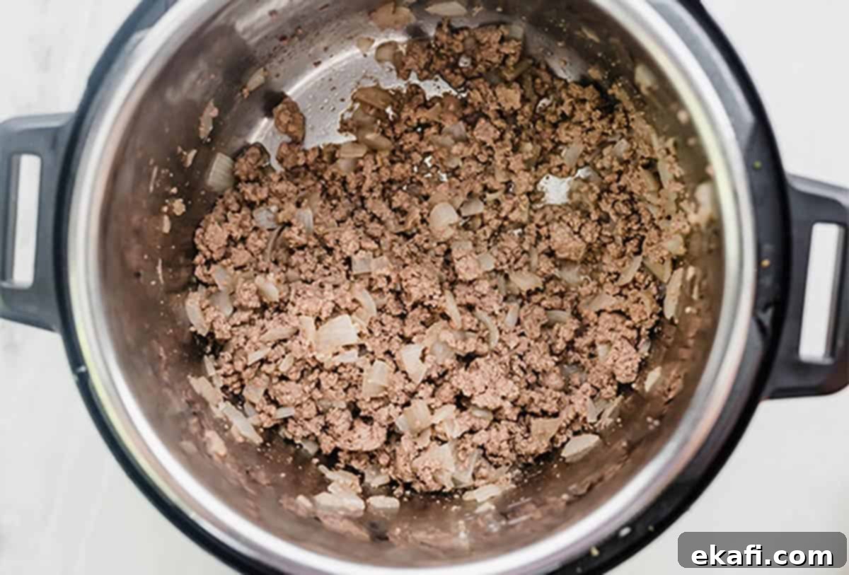 Instant Pot Ground Beef Stroganoff 4 Ground beef and diced onions cooking in an Instant Pot.