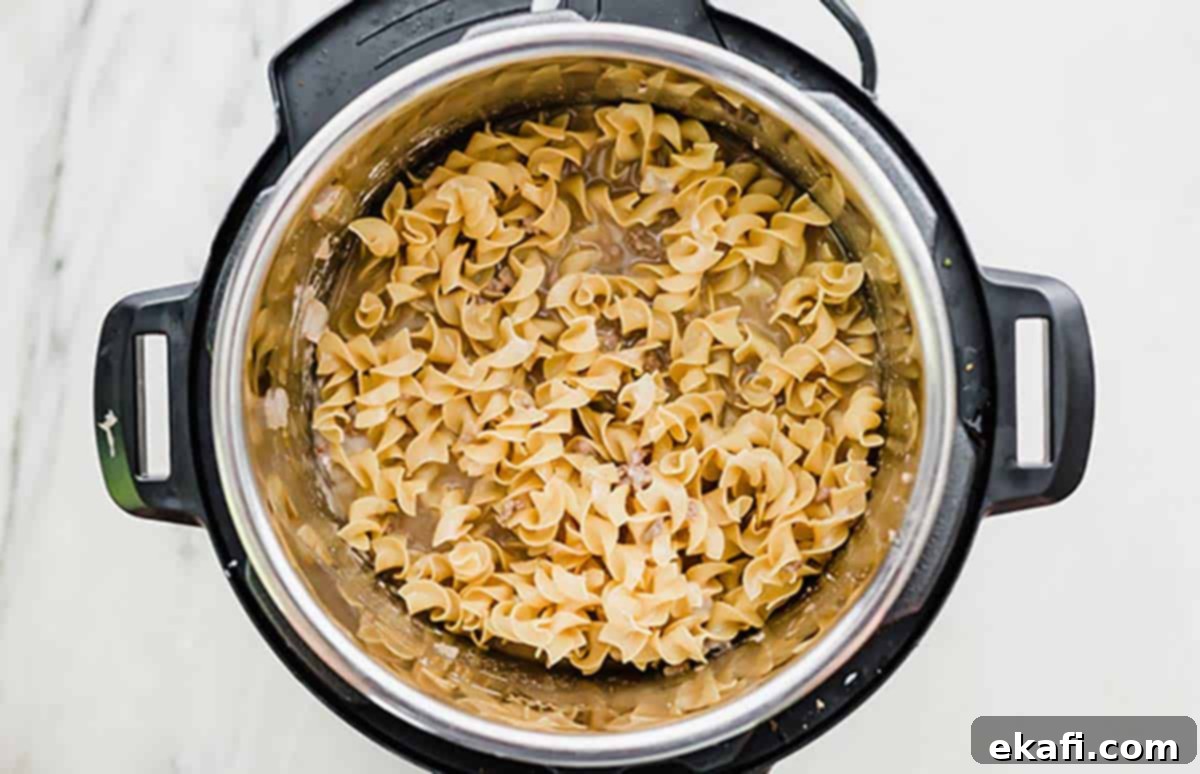 Instant Pot Ground Beef Stroganoff 5 Egg noodles added to the Instant Pot with other ingredients before pressure cooking.