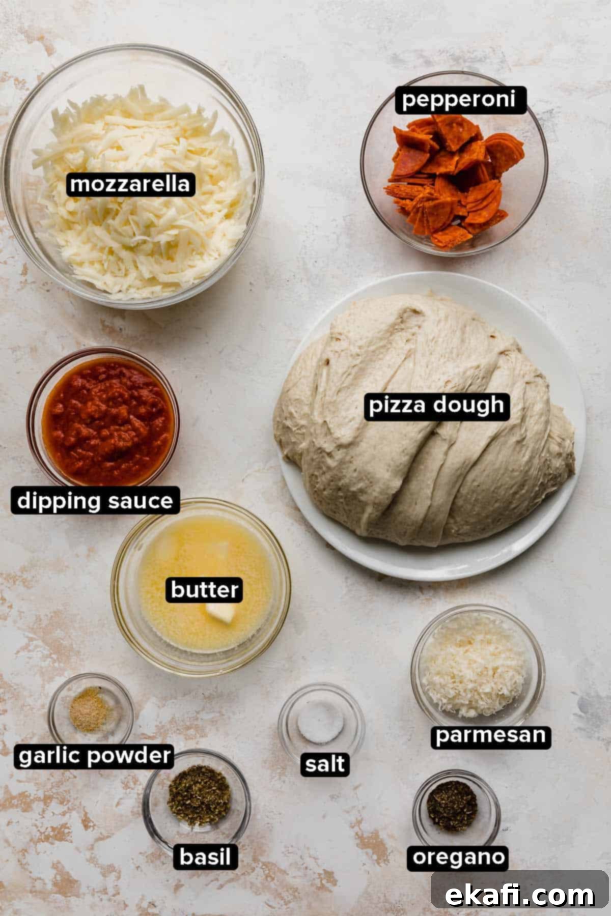 From-Scratch Pizza Rolls 3 Pizza Rolls ingredients laid out on a white textured background, including pizza dough, mozzarella, pepperoni, butter, and herbs.