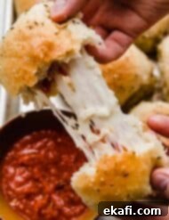 From-Scratch Pizza Rolls 8 Two hands pulling a pizza roll apart showing the stretchy mozzarella cheese and pepperoni inside, perfect for a delicious snack.