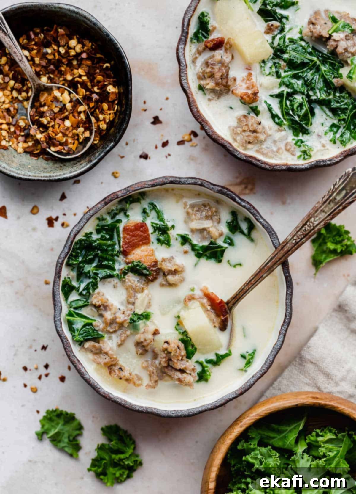 Copycat Olive Garden Zuppa Toscana 2 A black rimmed bowl filled with homemade Olive Garden Zuppa Toscana Soup, garnished with red pepper flakes.