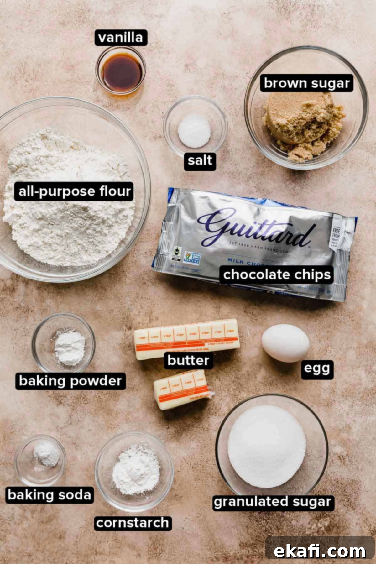 Copycat Crumbl Chocolate Chip Cookie Perfection 3 Crumbl Chocolate Chip Cookie Recipe ingredients laid out on a light brown background, including flour, sugars, butter, eggs, and large milk chocolate chips.