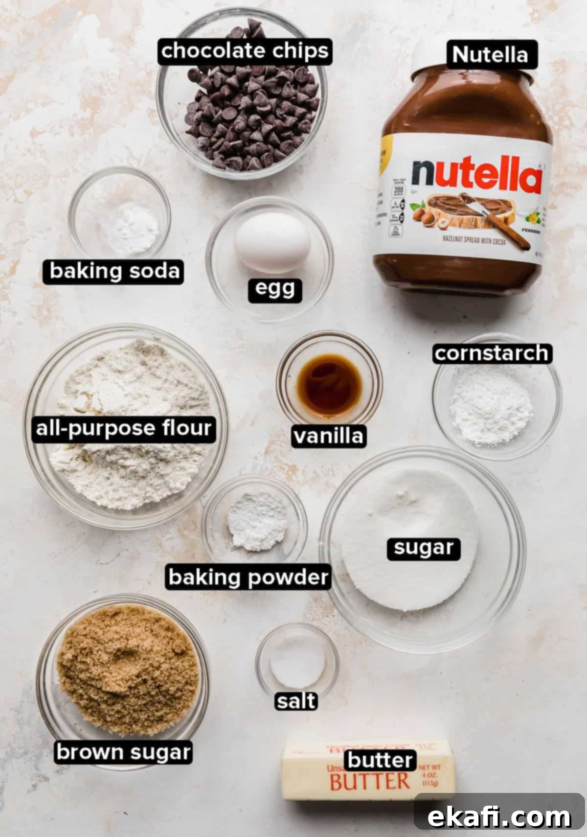 Nutella Lava Kurabiyeleri 3 All ingredients for Nutella Stuffed Nutella Cookies, including butter, sugars, Nutella, egg, and flour, neatly arranged in glass bowls on a white background.