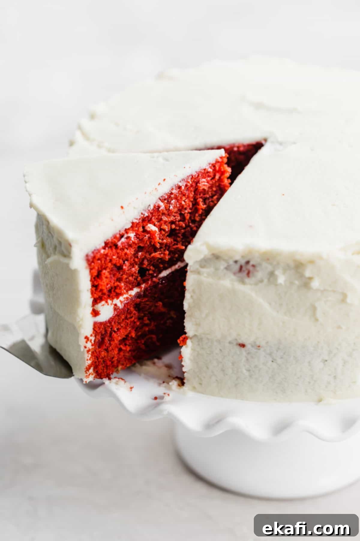 Heirloom Red Velvet Cake 8 A beautifully frosted two-layer Old Fashioned Red Velvet Cake standing proudly on a white cake stand against a pristine white background.