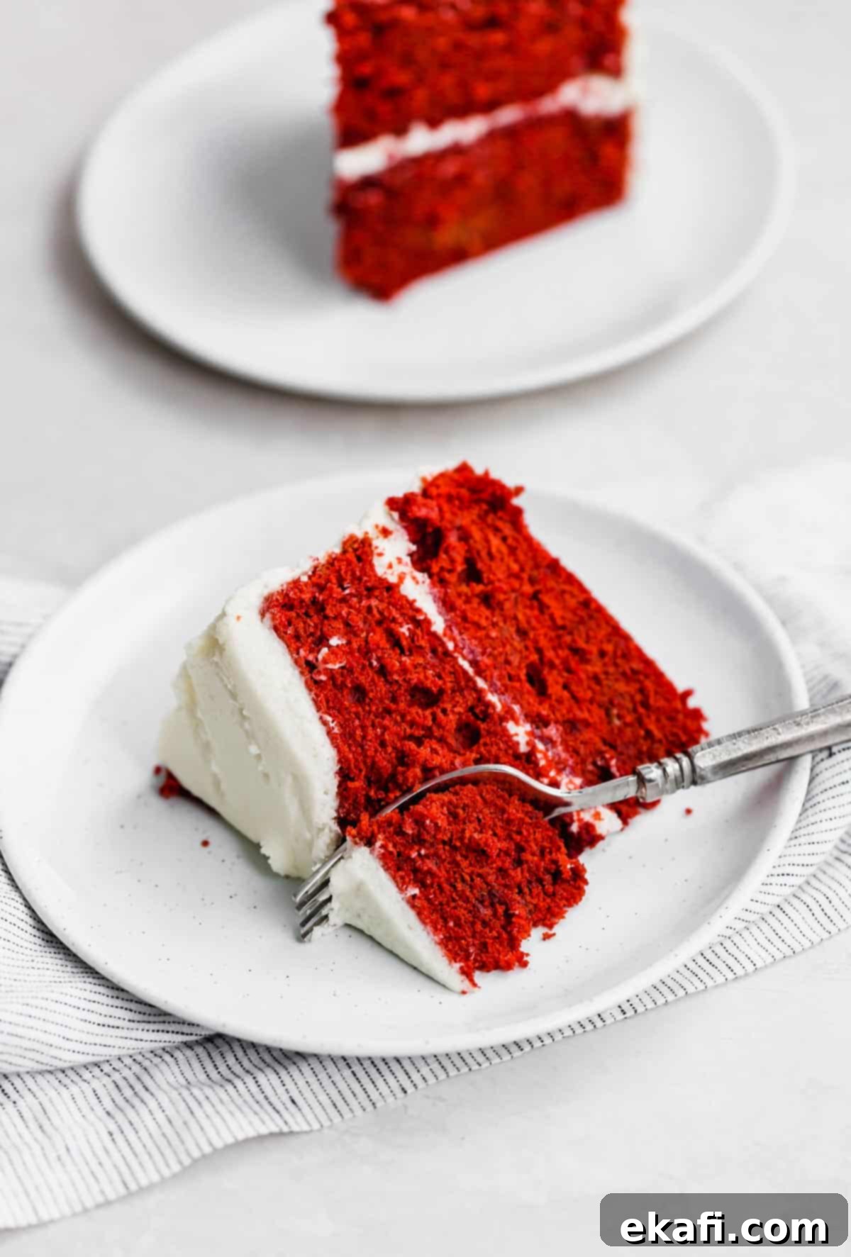 Heirloom Red Velvet Cake 10 A delectable slice of Old Fashioned Red Velvet Cake, topped generously with creamy white old fashioned frosting, served on a crisp white plate.