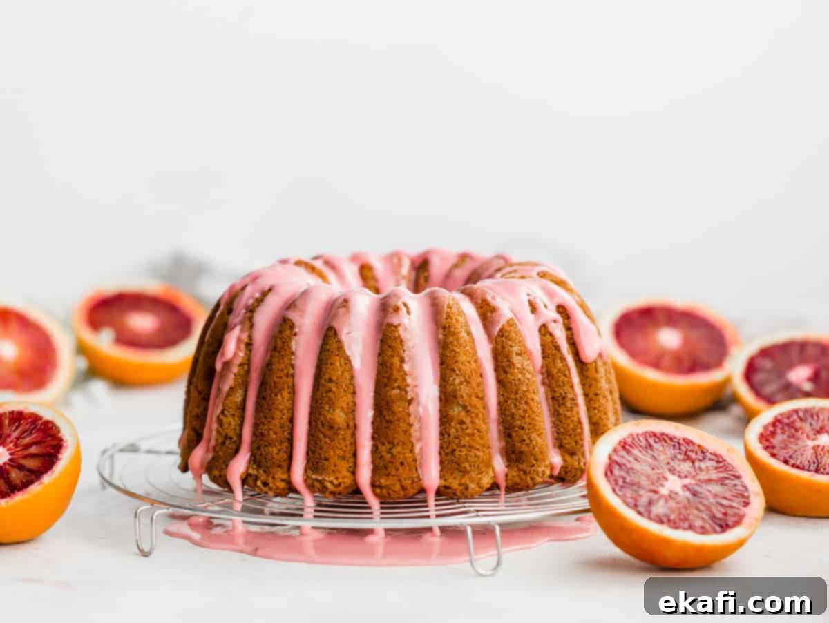 Vibrant Blood Orange Bundt Cake 9 Close-up of vibrant pink glaze flowing down the elegant ridges of a bundt cake on a white background.