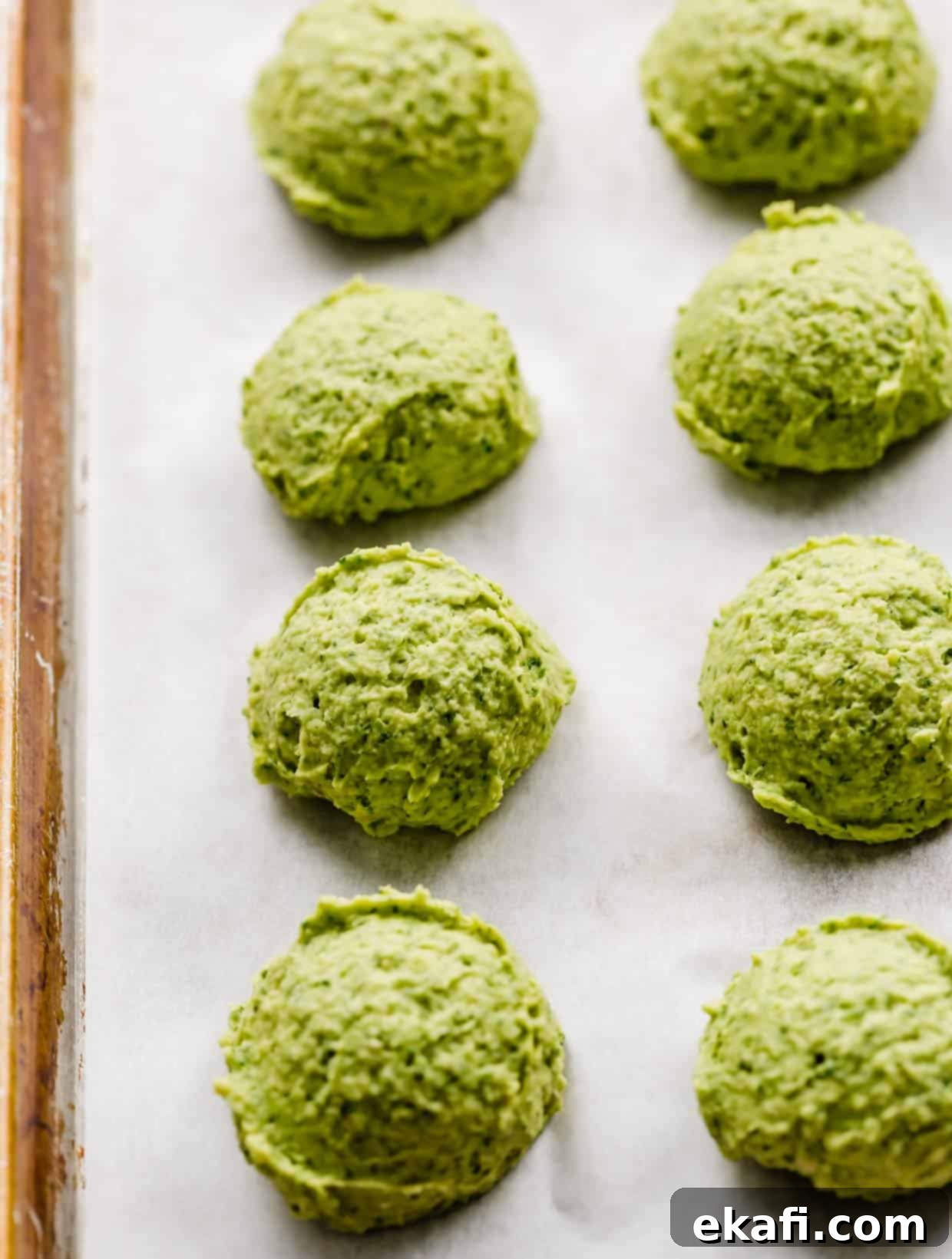 Fresh Herb Falafel 6 Unbaked green falafel rounds on a white parchment lined baking sheet.