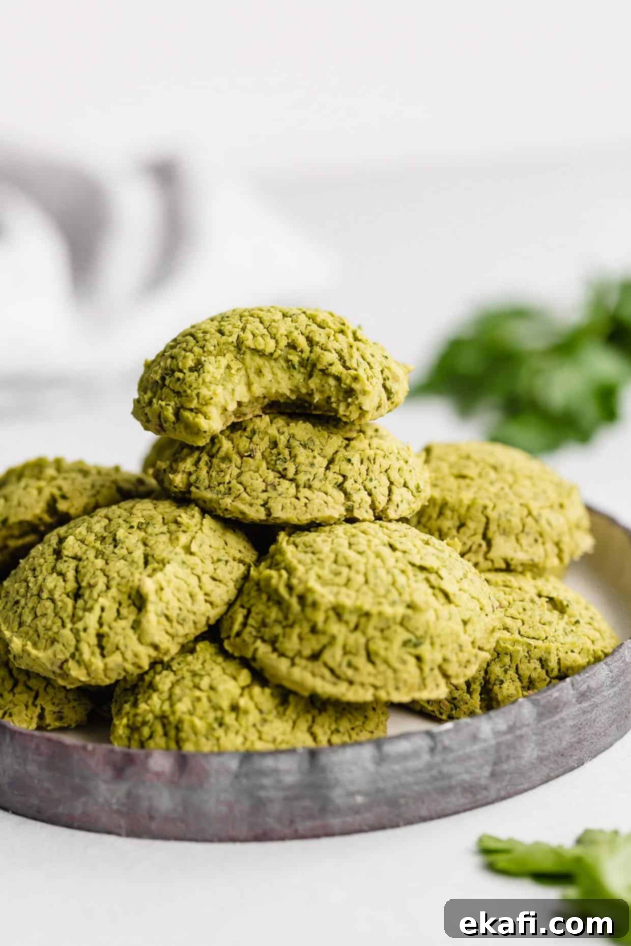 Fresh Herb Falafel 7 Baked Falafel on a black plate with the top falafel having a bite removed from it.