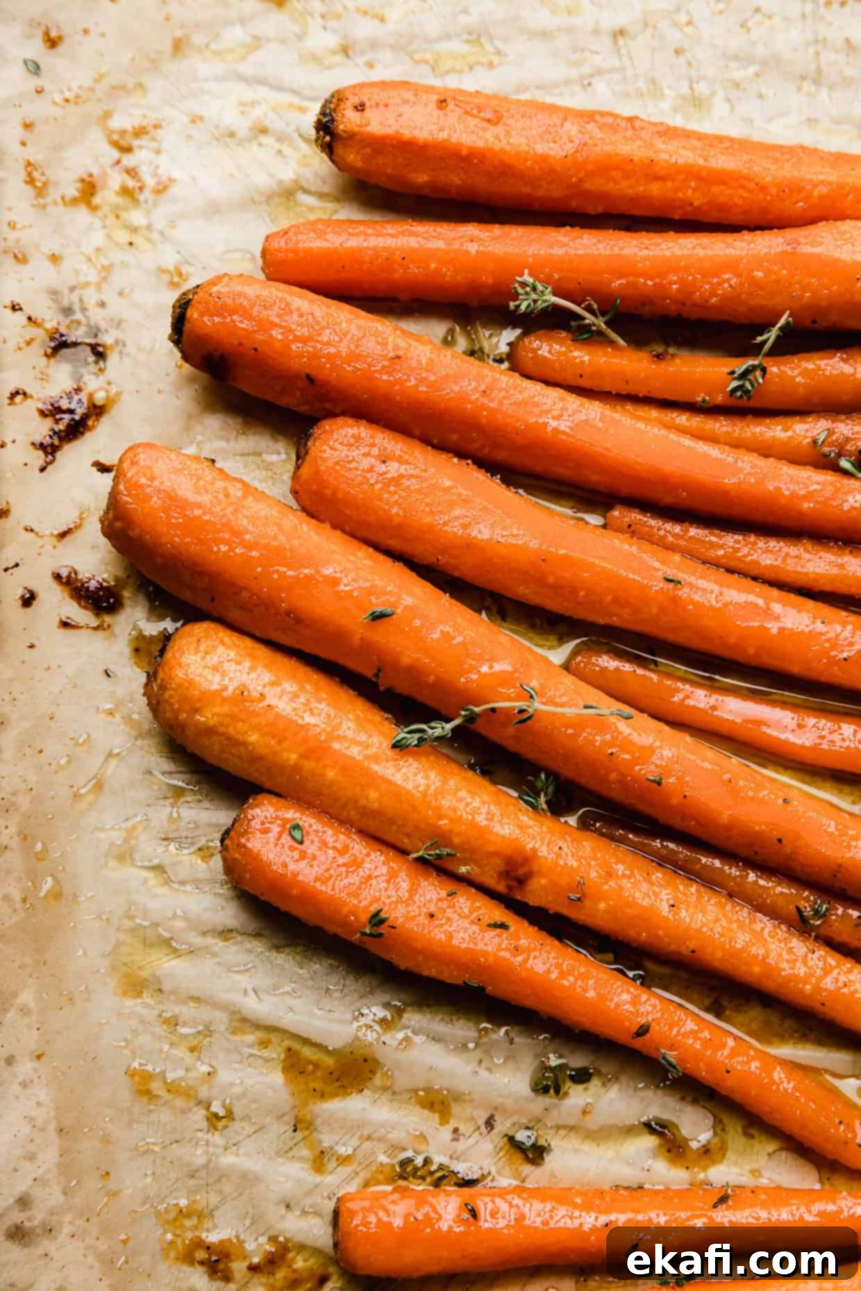 Καραμελωμένα Καρότα Καστανής Ζάχαρης 2 Brown Sugar Roasted Carrots with thyme on a tan parchment paper.
