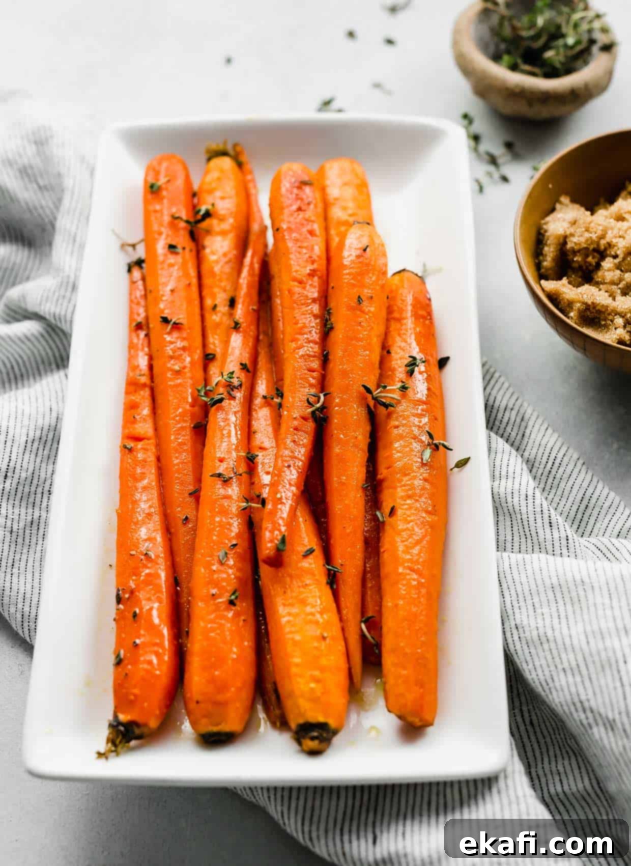 Καραμελωμένα Καρότα Καστανής Ζάχαρης 8 Brown Sugar Roasted Carrots topped with fresh thyme on a white plate.