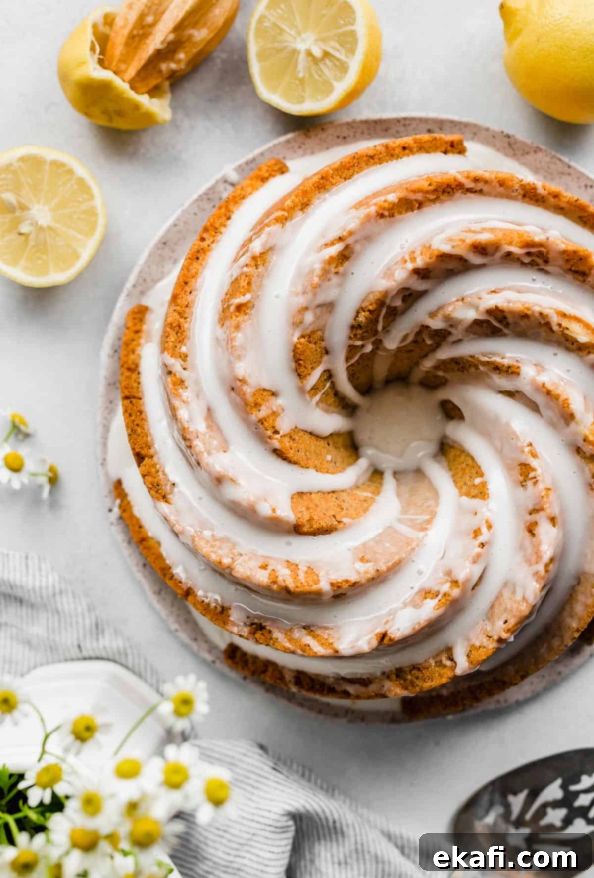 Zesty Lemon Poppy Seed Crown 2 An overhead photo of a Lemon Poppy Seed Bundt Cake topped with a white glaze with sliced lemons around the cake.