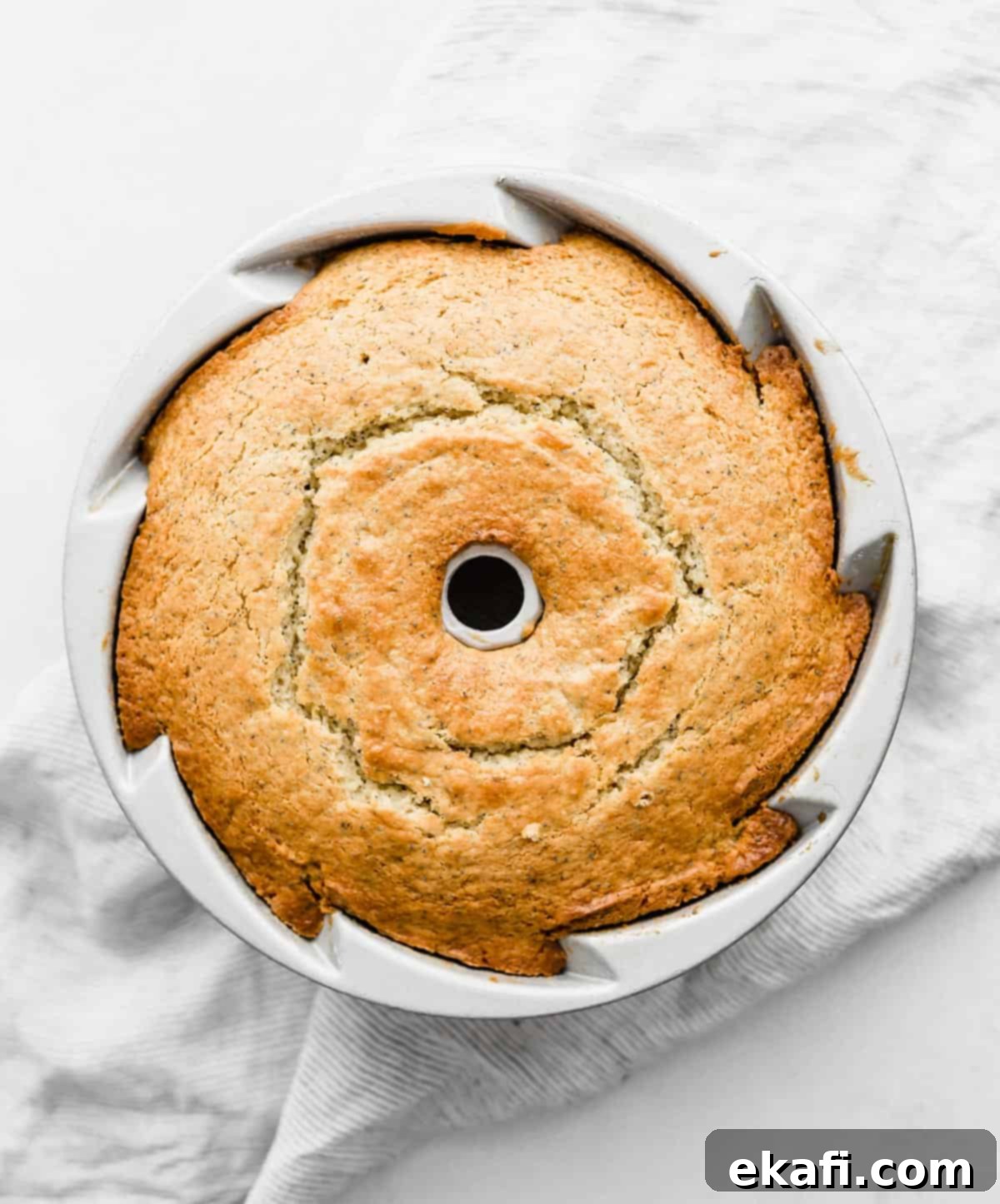 Zesty Lemon Poppy Seed Crown 5 A baked Lemon Poppy Seed cake in a bundt pan on a white background.