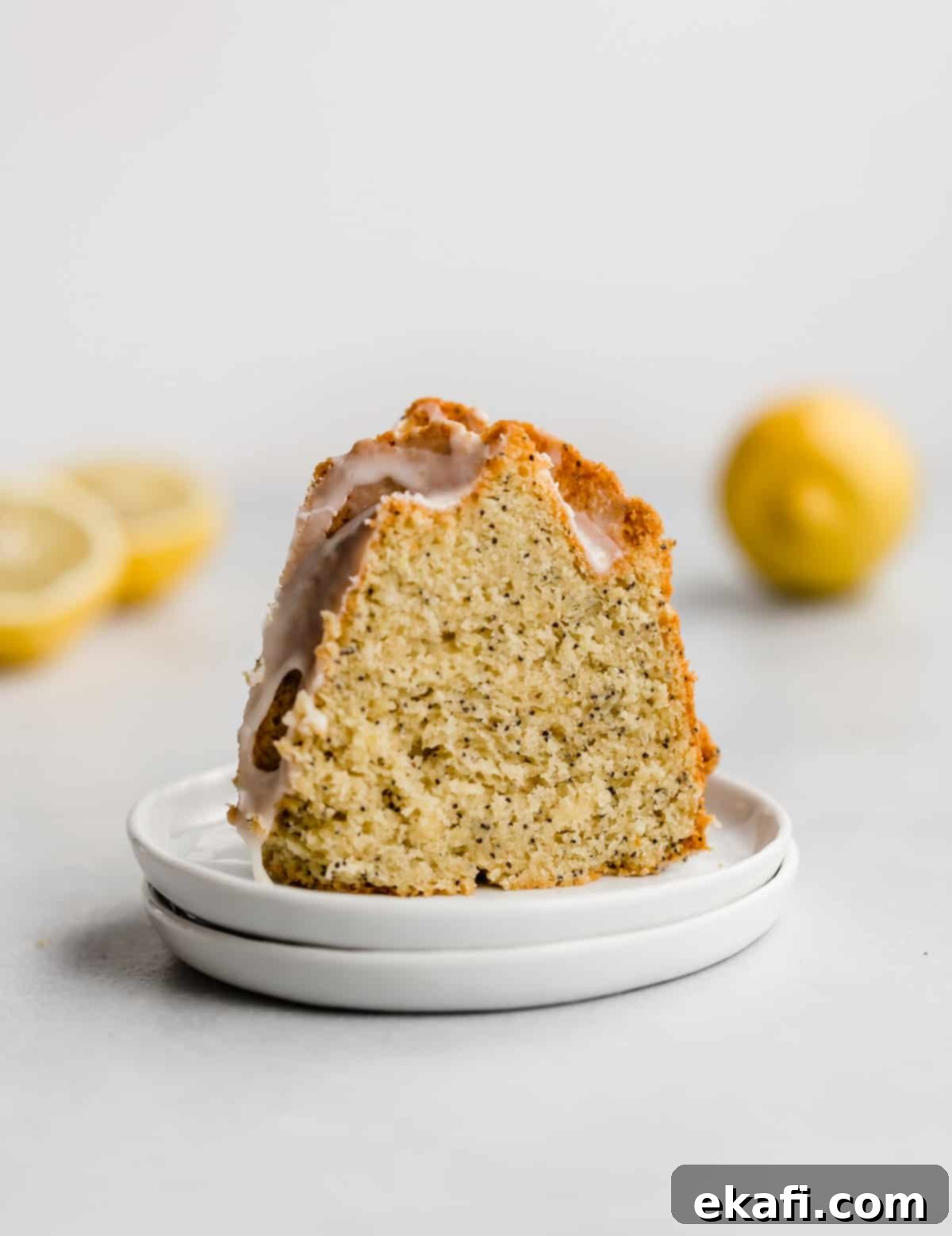 Zesty Lemon Poppy Seed Crown 7 A slice of Lemon Poppy Seed Bundt Cake on a white plate.