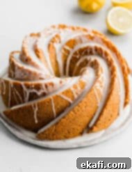 Zesty Lemon Poppy Seed Crown 9 A Lemon Poppy Seed Bundt Cake topped with a white glaze on a white background.