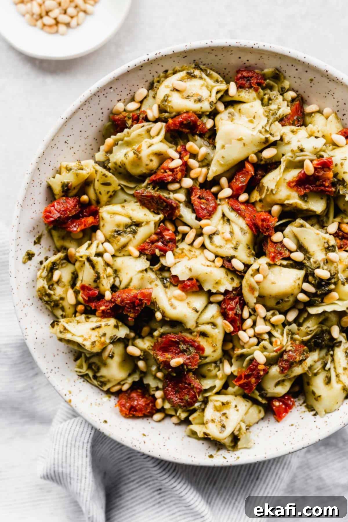 Pesto-Kissed Tortellini 2 Pesto Tortellini Pasta Salad with sun-dried tomatoes and pine nuts.