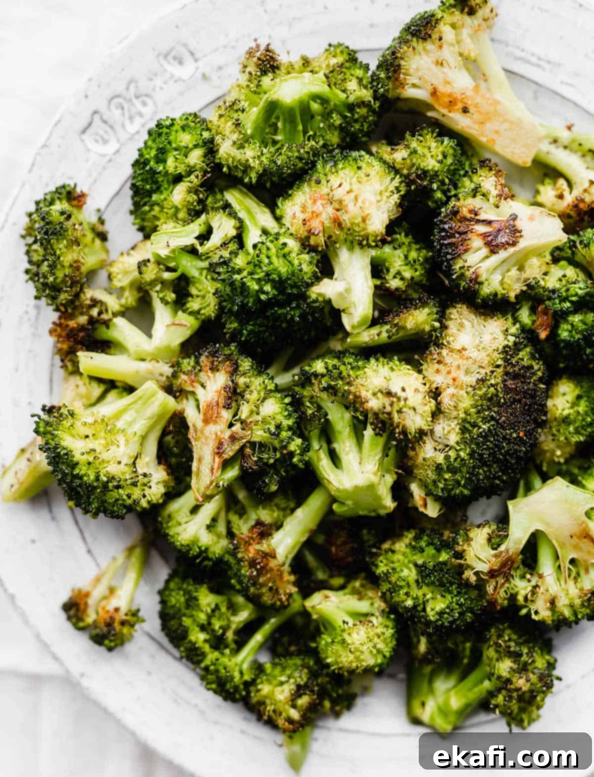 Crispy Oven Roasted Broccoli 2 Oven Roasted Broccoli on a white plate, showcasing its crispy, golden-brown edges.