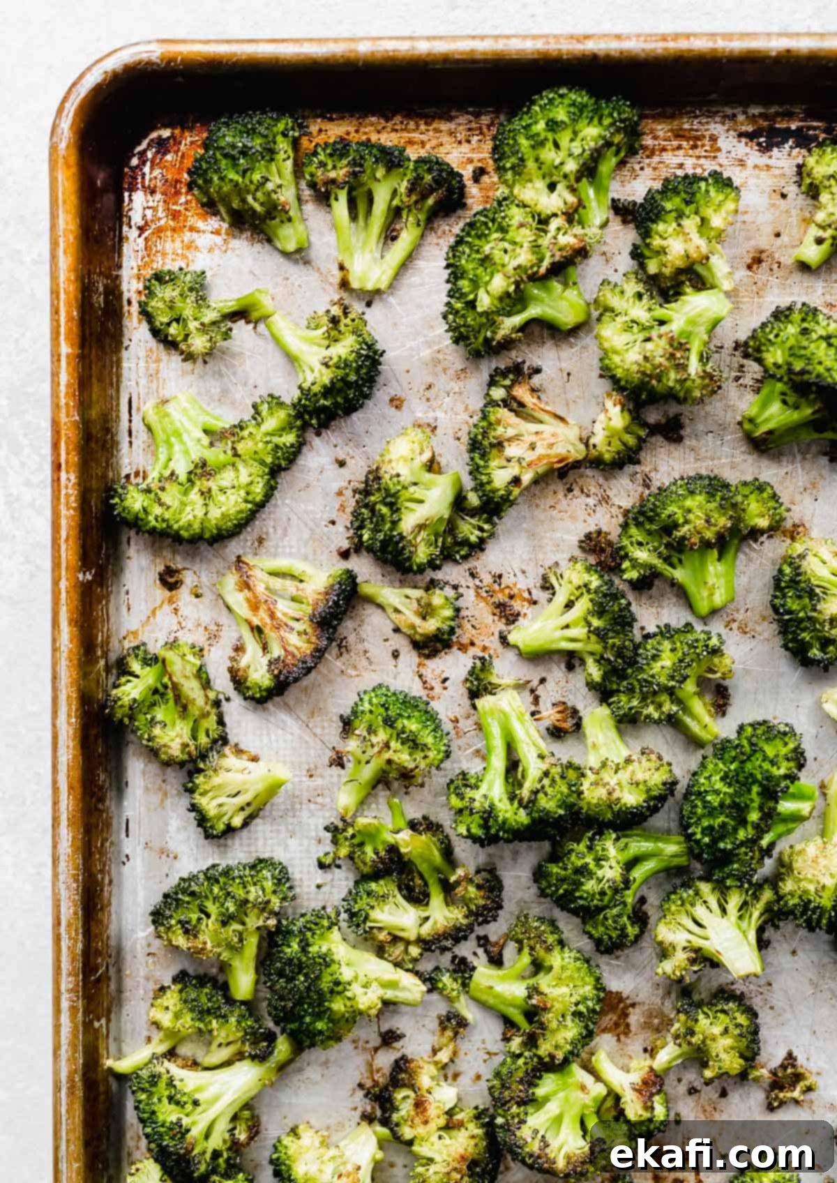 Crispy Oven Roasted Broccoli 5 Easy Roasted Broccoli florets freshly removed from the oven, showing their golden color and crisp texture on a baking sheet.