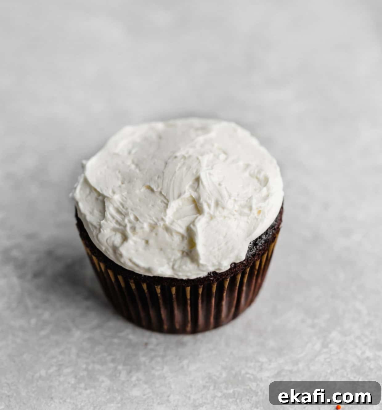 Μπασκετικά Κάπκεϊκς 4 Ένα σοκολατένιο cupcake με επικάλυψη ελβετικής βουτυρόκρεμας μαρέγκας σε γκρι φόντο.