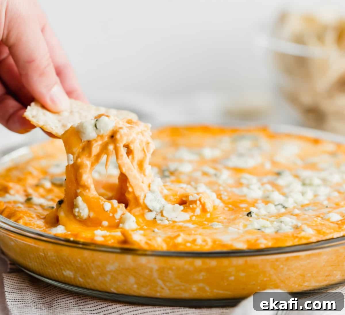 Ultimate Buffalo Chicken Dip 2 A tortilla chip dipping into buffalo chicken dip with blue cheese.