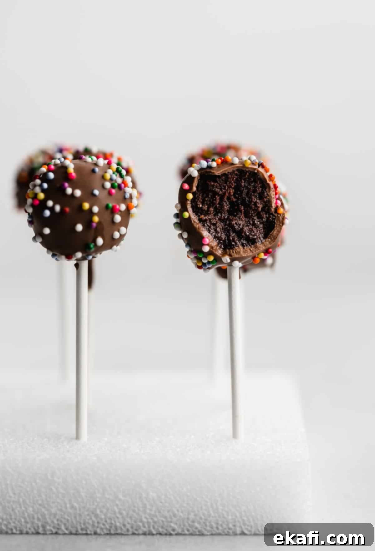Κεκάκια Ποπ Σοκολάτας 7 Σοκολατένια Cake Pops σε έναν λευκό κύβο από φελιζόλ με ένα cake pop δαγκωμένο.