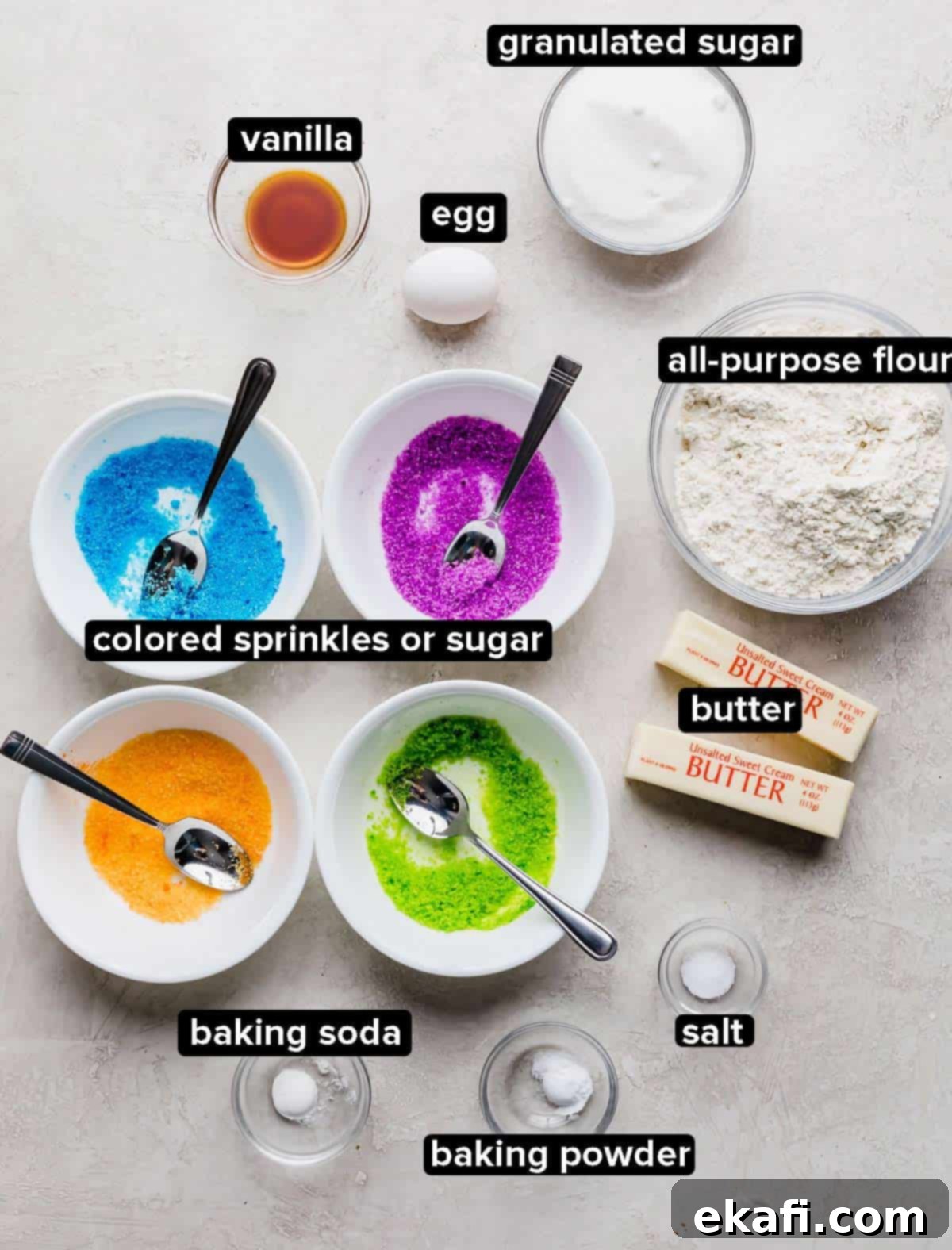 Sugared Delights 3 A collection of ingredients for sugar coated cookies, including butter, sugar, eggs, flour, and colored sugar, neatly arranged on a light gray background.