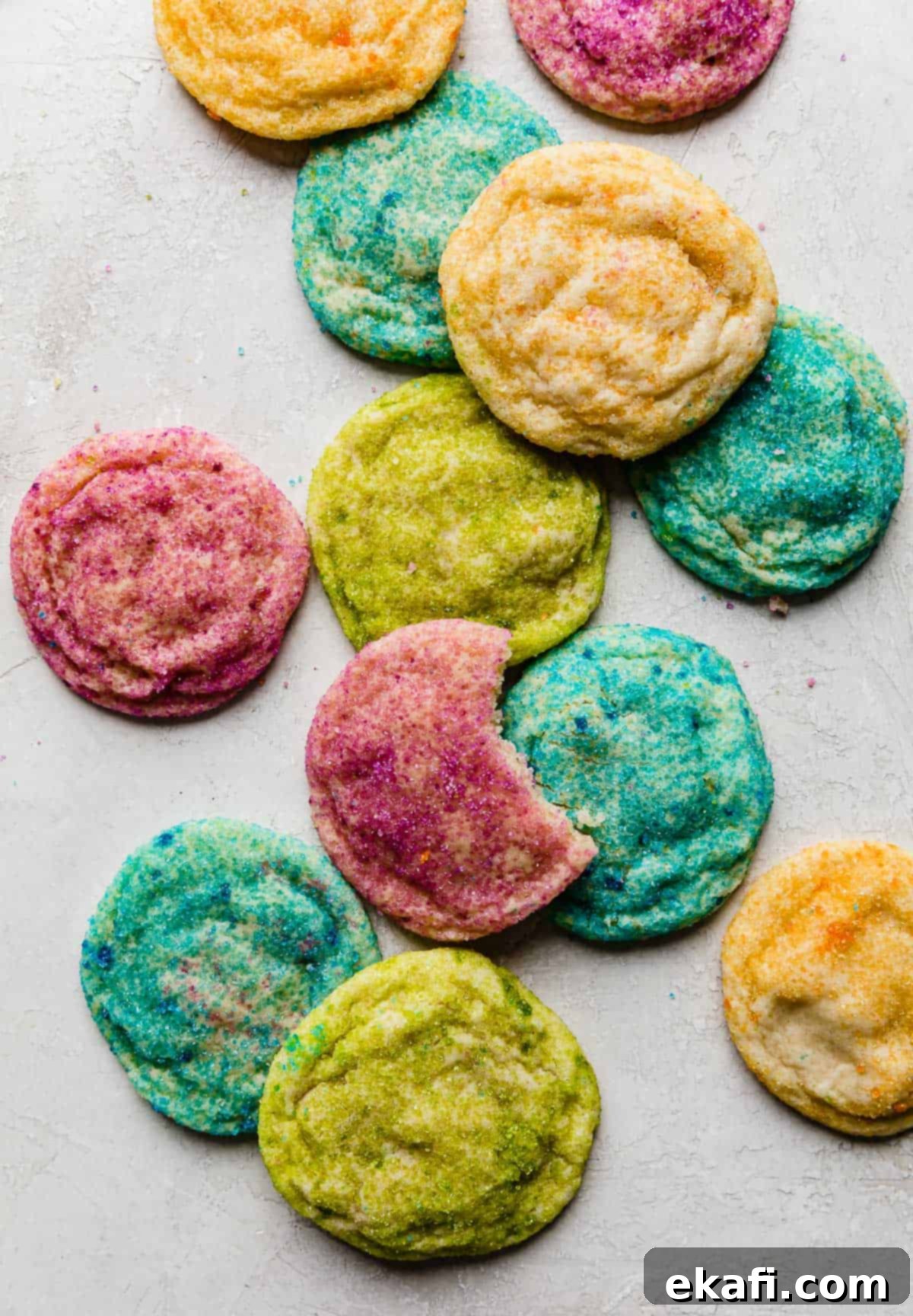 Sugared Delights 9 A delightful arrangement of purple, blue, yellow, and green sugar coated cookies on a pristine white background, showcasing their festive appeal.