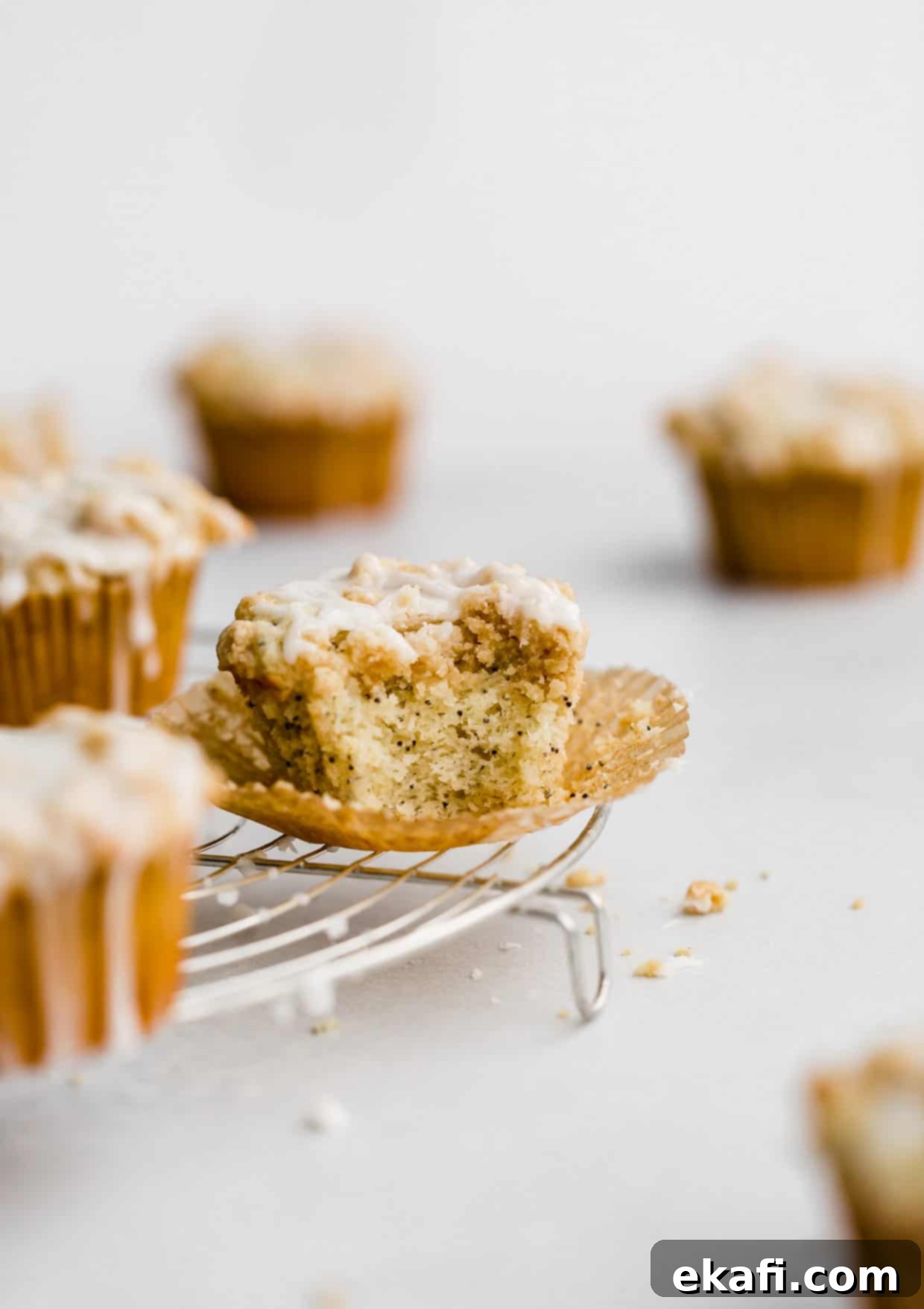 Ultra Moist Lemon Poppy Seed Muffins with Sour Cream 2 A perfectly baked Lemon Poppy Seed Muffin with a bite taken out, revealing its moist crumb and scattered poppy seeds, resting on a circular wire cooling rack.