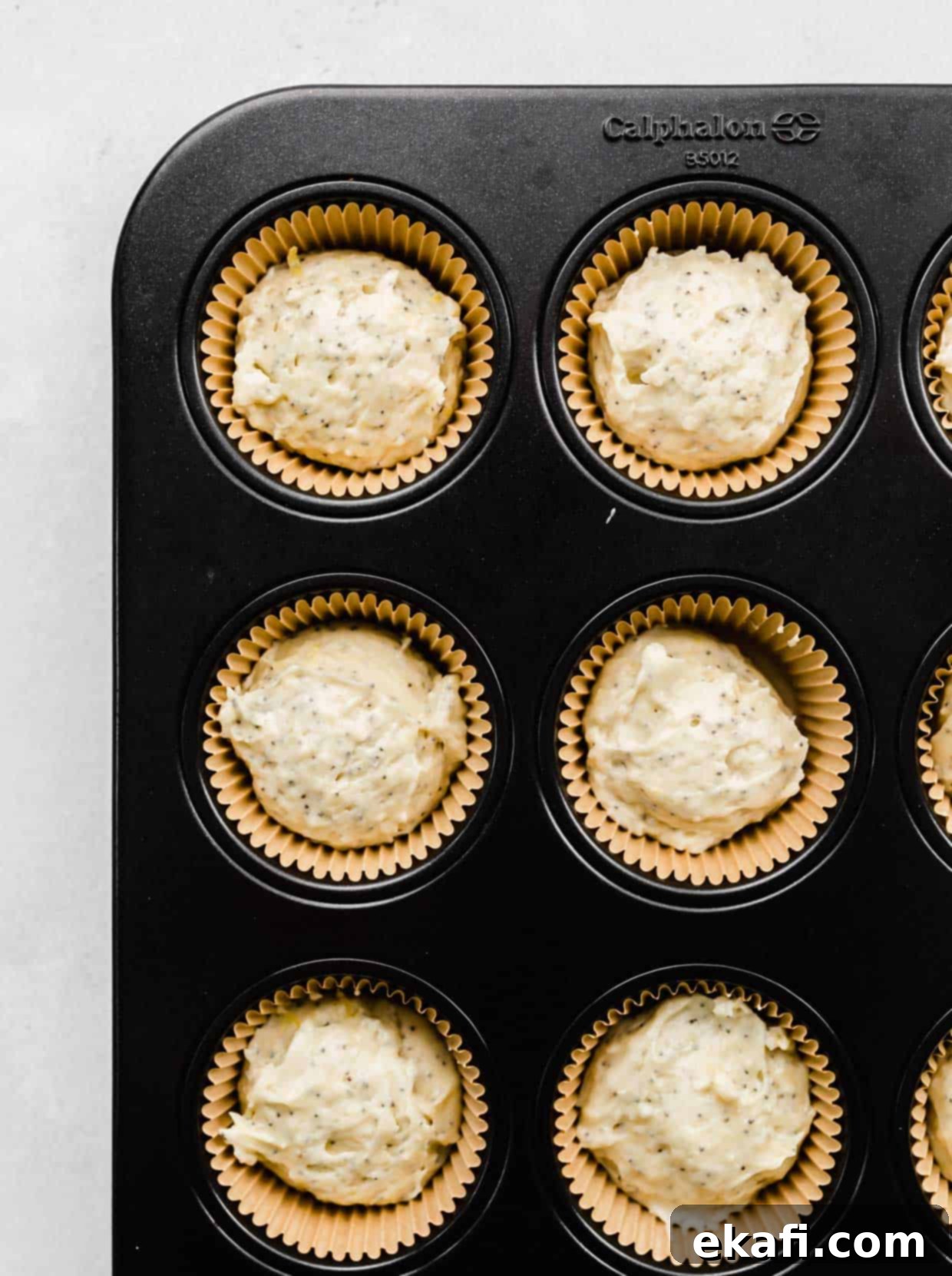 Ultra Moist Lemon Poppy Seed Muffins with Sour Cream 6 Raw Lemon Poppy Seed Muffin batter neatly scooped into Kraft paper lined muffin tins, ready for the topping.