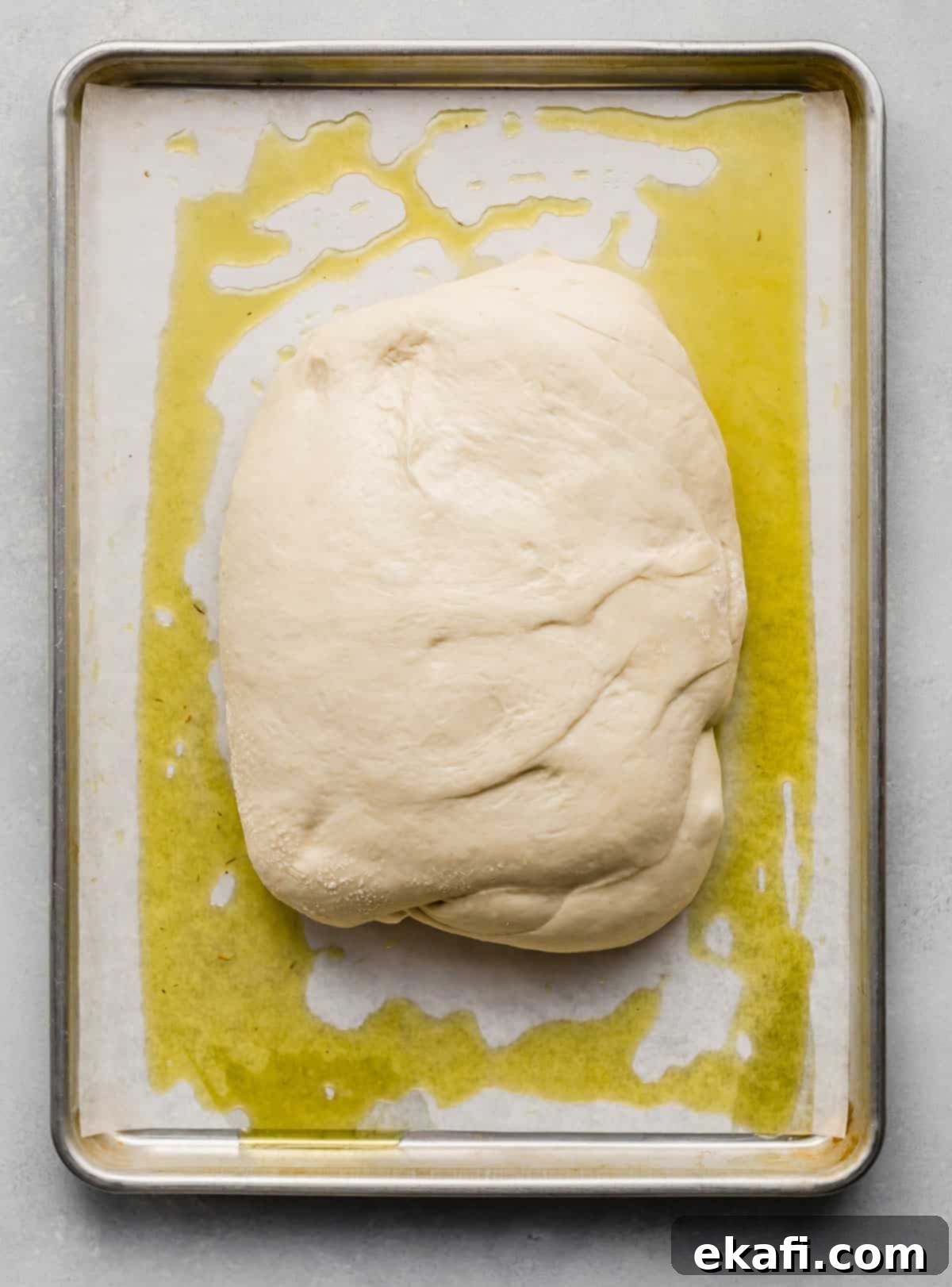 Artisanal Focaccia Bread 5 Focaccia Bread dough shaped in a rectangle on an oil covered baking sheet.