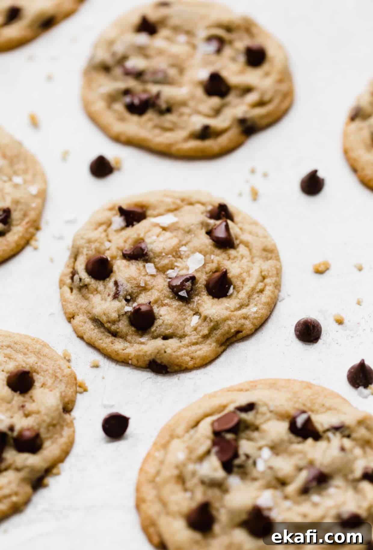 Sweet and Savory Tahini Chocolate Chip Cookies 2 Tahini Chocolate Chip Cookies topped with sea salt on a white background, showcasing their soft texture.