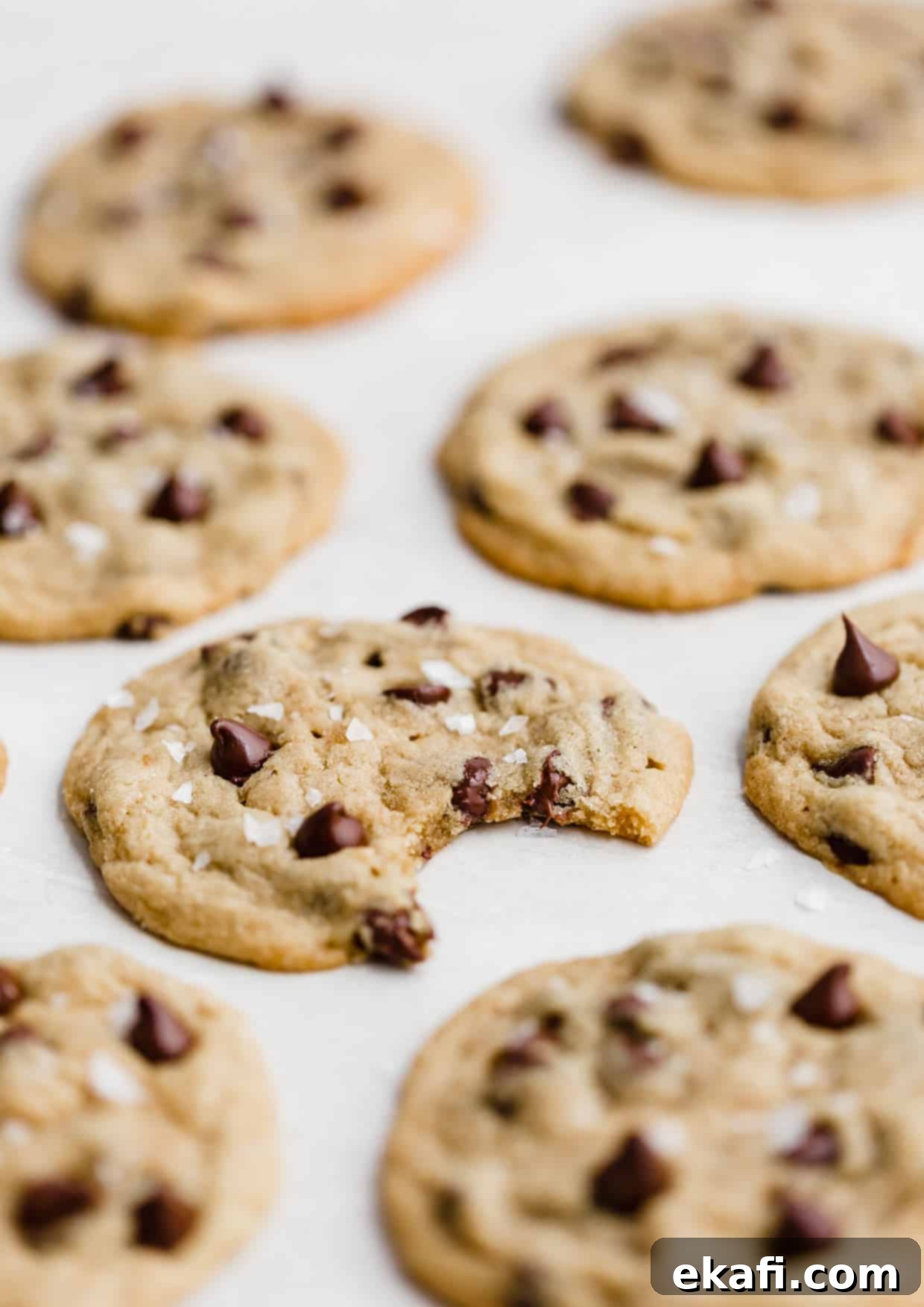 Sweet and Savory Tahini Chocolate Chip Cookies 8 A bite taken out of a Tahini Chocolate Chip Cookie that's on a white background, highlighting its soft interior.