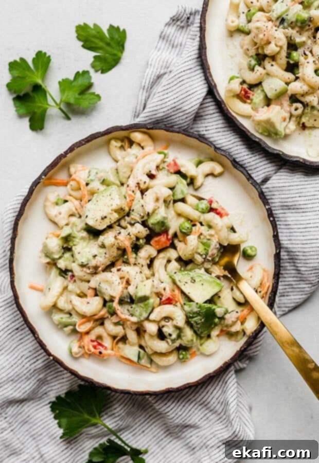 Creamy Tuna Avocado Macaroni Salad 3 A gold spoon scooping up a mixed vegetable and tuna macaroni salad, highlighting its creamy texture.
