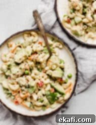 Creamy Tuna Avocado Macaroni Salad 9 A macaroni salad loaded with vegetables on a plate.