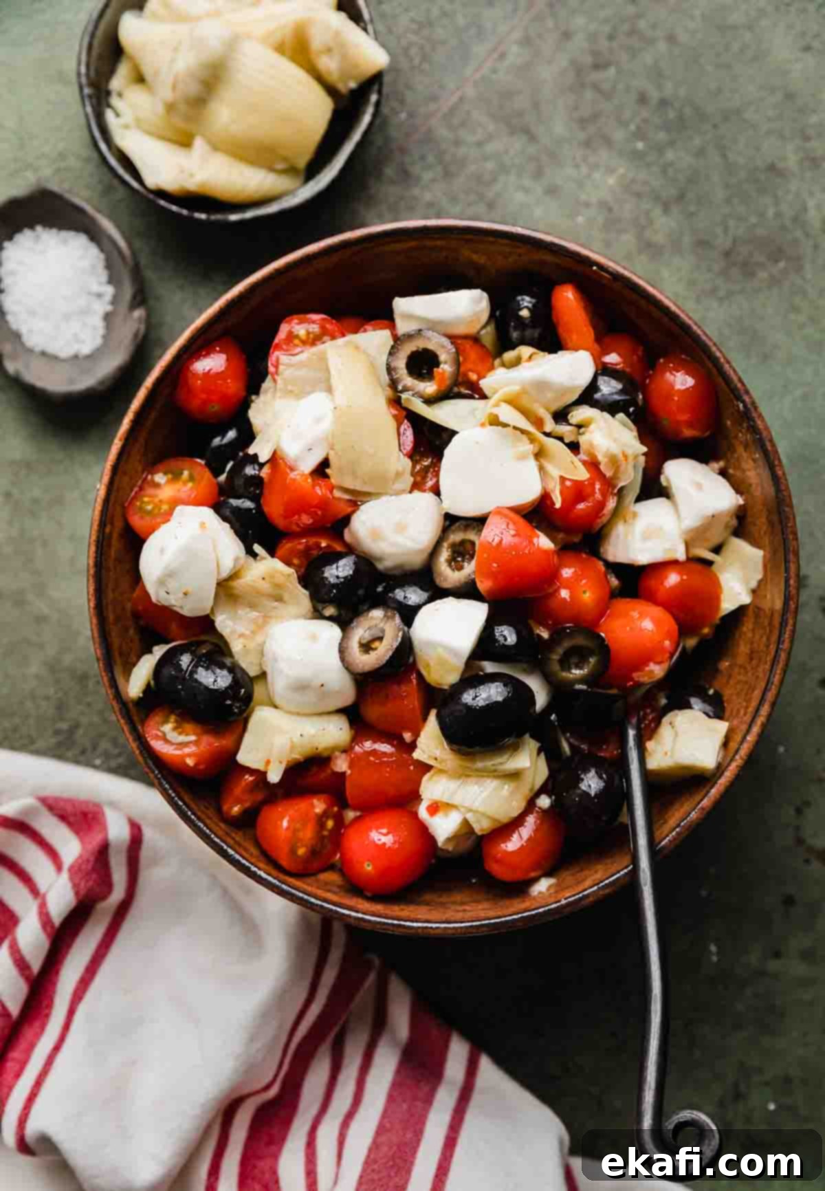 Fresh Tomato Artichoke Salad 6 A rustic brown bowl generously filled with a vibrant Tomato Artichoke Salad, ready to be enjoyed.