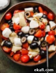 Fresh Tomato Artichoke Salad 7 A close-up shot of the fresh and colorful Tomato Artichoke Salad in a rustic brown bowl, presented on a vibrant green background, emphasizing its delicious texture.