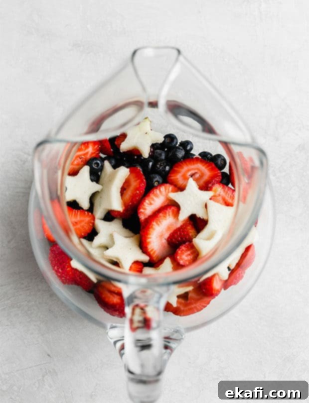 Red White and Blue Refresher 4 A red, white, and blue fruit filled glass pitcher against a white background.