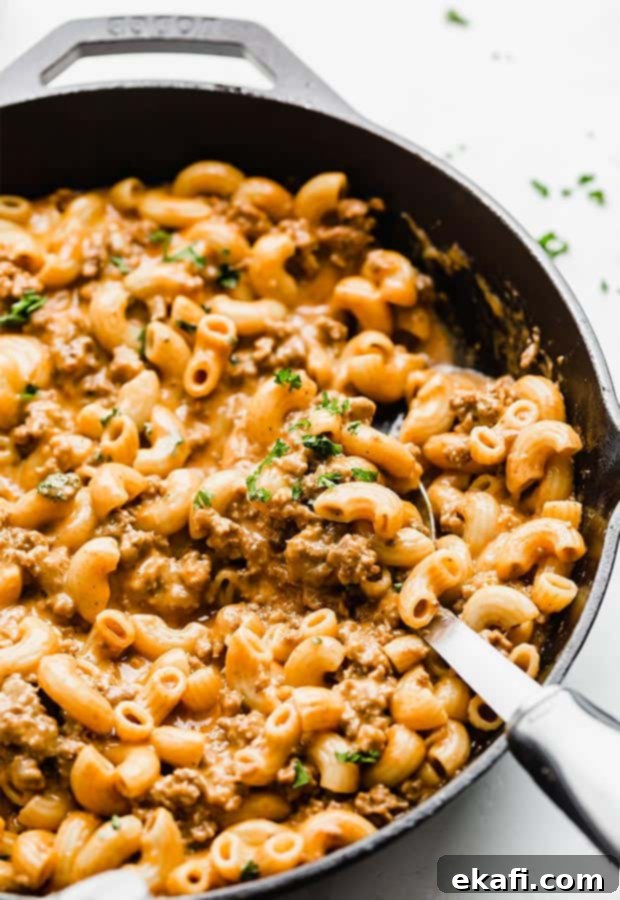 Homemade Cheesy Beef Pasta Skillet 8 A large spoon in scooping up a homemade meat and cheese pasta.